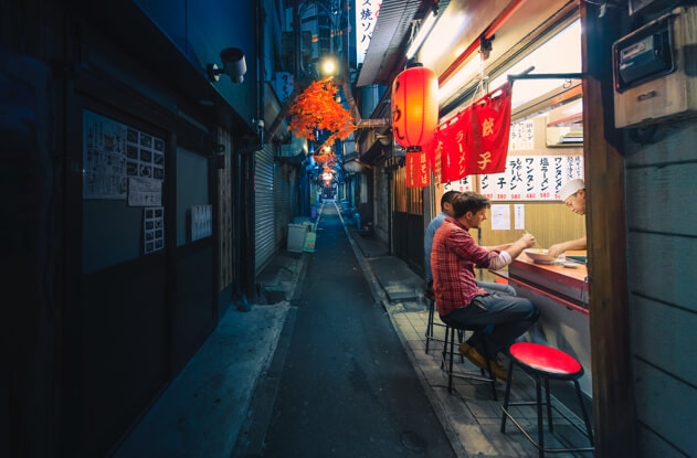 Two friends dine at a soup street vendor at night