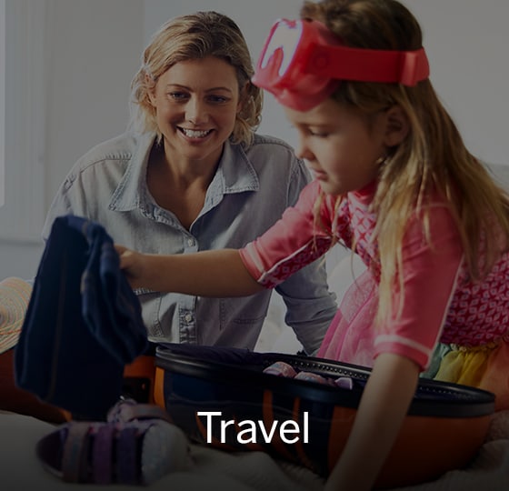 Child packing little suitcase with clothes. Mother in background smiling. Text over image - Travel.