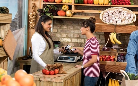 A lady making payment at a grocery shop.