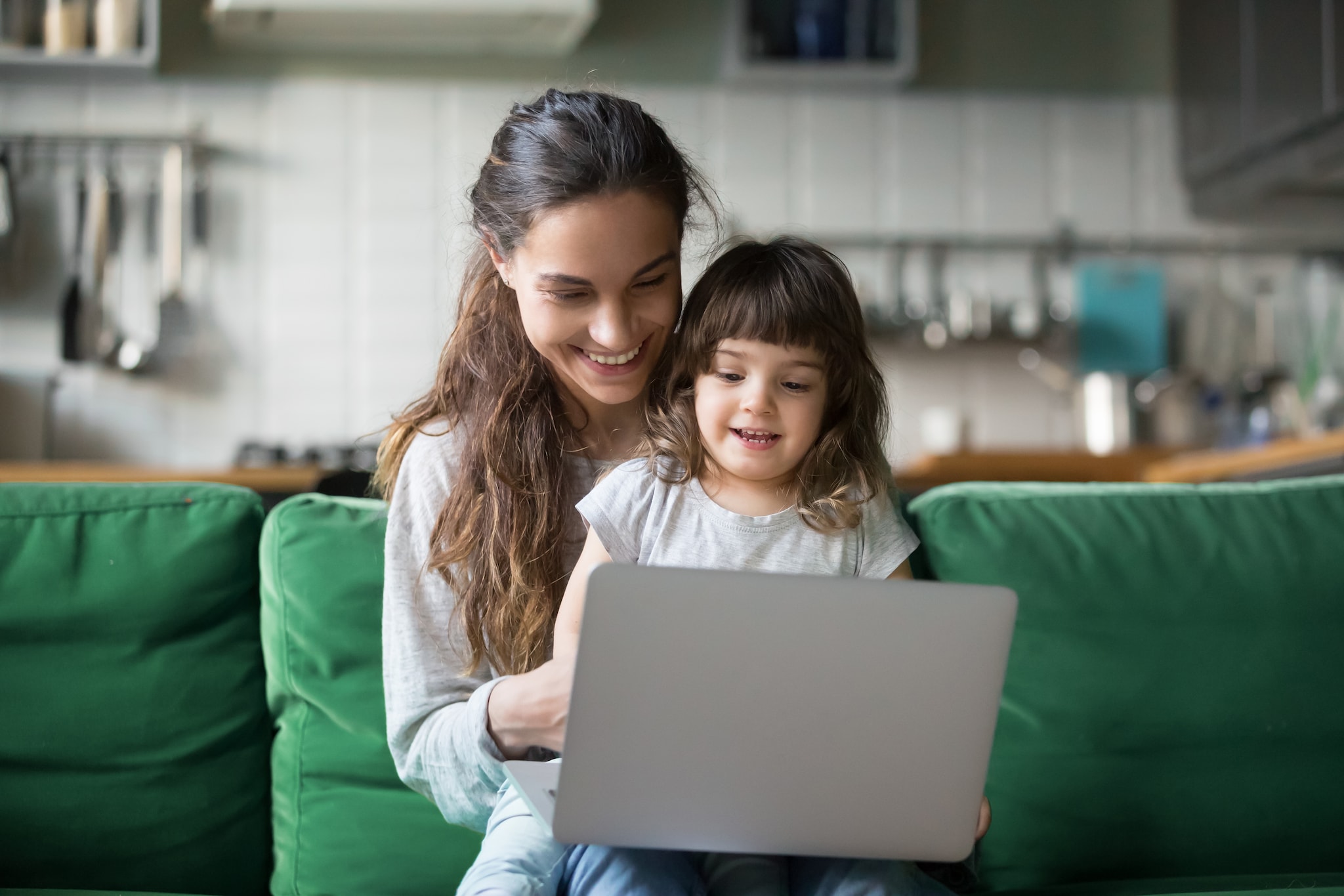 A lady and a kid on her lap checking the laptop. 