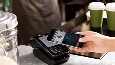 Making payment using smartphone by holding it up to a contactless reader at a cafe.