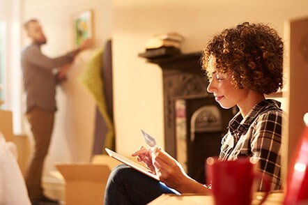 A lady holding Amex Card enters Card details on her device.