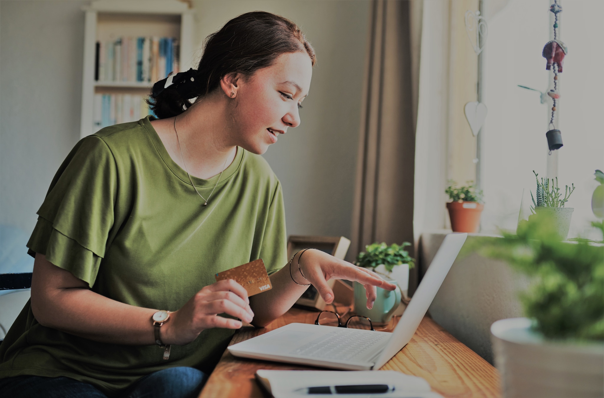  A lady holding an Amex Card checking her laptop.