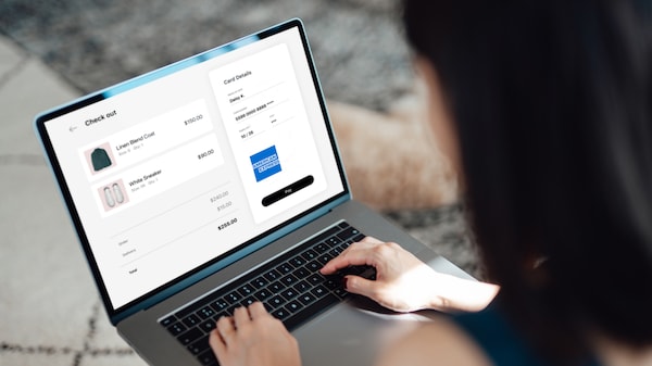 Person shopping on laptop with Amex logo at checkout