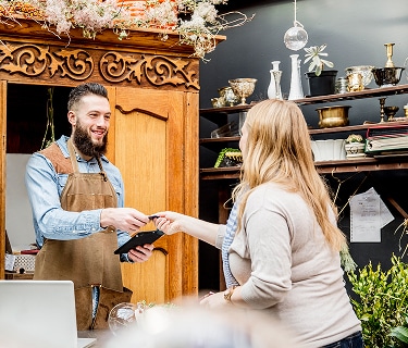 Woman handing credit card to shop store owner at checkout