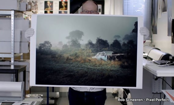 Rob Scheeren - Pixel Perfect standing in shop and holding print