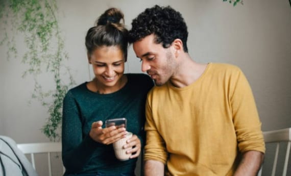 Man and woman sitting on chairs and looking at mobile device
