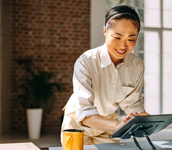Small business owner standing at checkout and tapping on tablet device