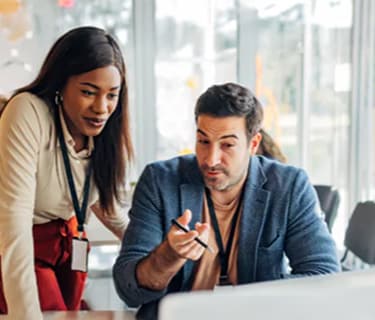 Coworkers in an office looking at a laptop