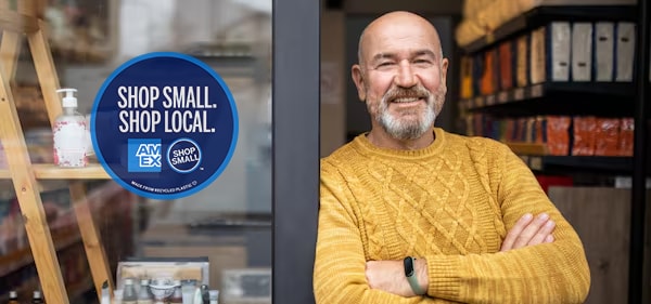 Merchant in storefront with Shop Small with Amex sign in window