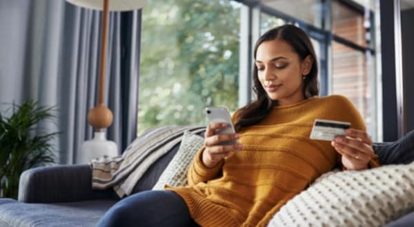 Woman sitting on couch activating Amex Card through Amex App	