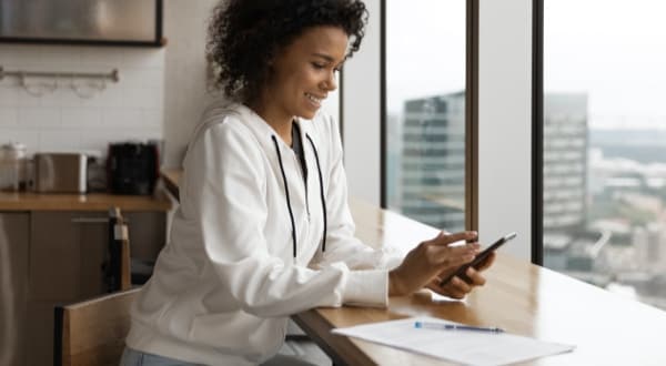 Woman by window checking paperless credit card statements on Amex App