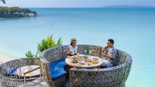 Two people eating a meal by the beach