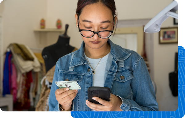 Fashion designer looking at her phone to check on her American Express account.