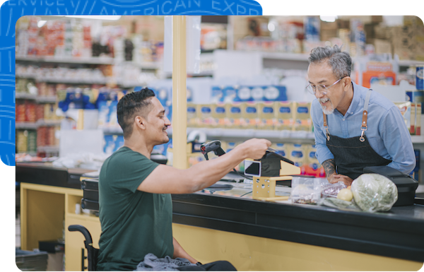 Asian Indian man in a wheelchair uses his American Express credit card to complete his purchase at a supermarket.