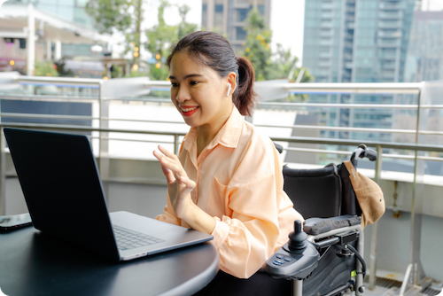 Woman sitting at table looking at laptop and smiling