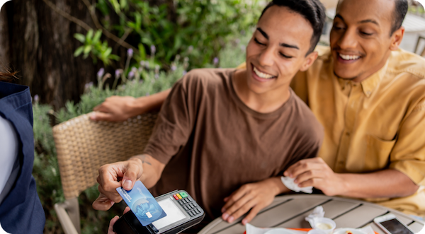 A couple paying with American Express credit card at table by tapping contactless terminal