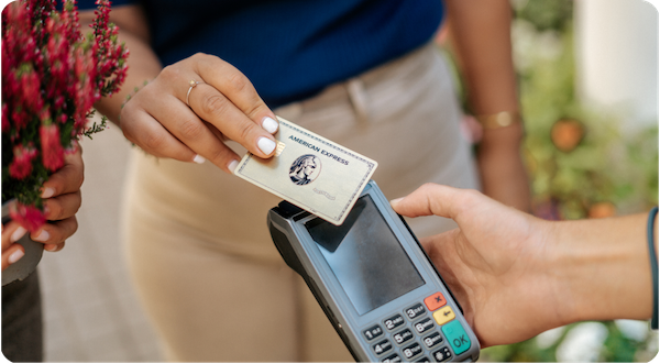 Woman paying with American Express Gold card at payment terminal