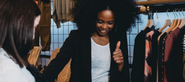 Woman behind the counter of a retail shop and giving a thumbs up