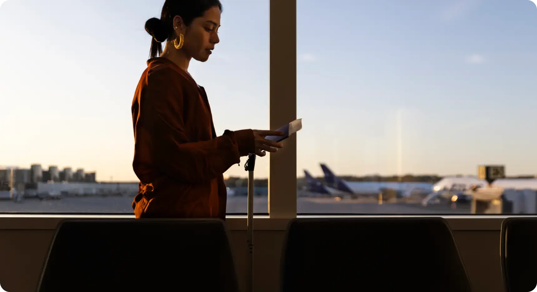 Frau steht am Flughafenfenster und überprüft Reisepass und Unterlagen vor dem Abflug.