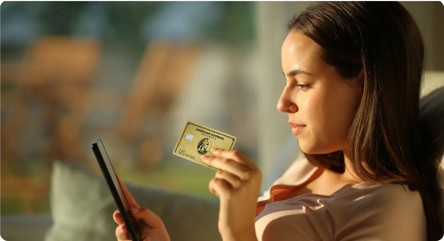 Frau hält eine Business Gold Card in der Hand und schaut auf ihr Smartphone