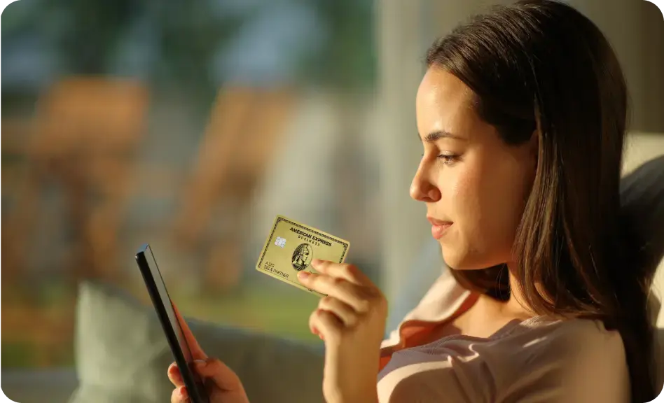 Frau hält eine Business Gold Card in der Hand und schaut auf ihr Smartphone