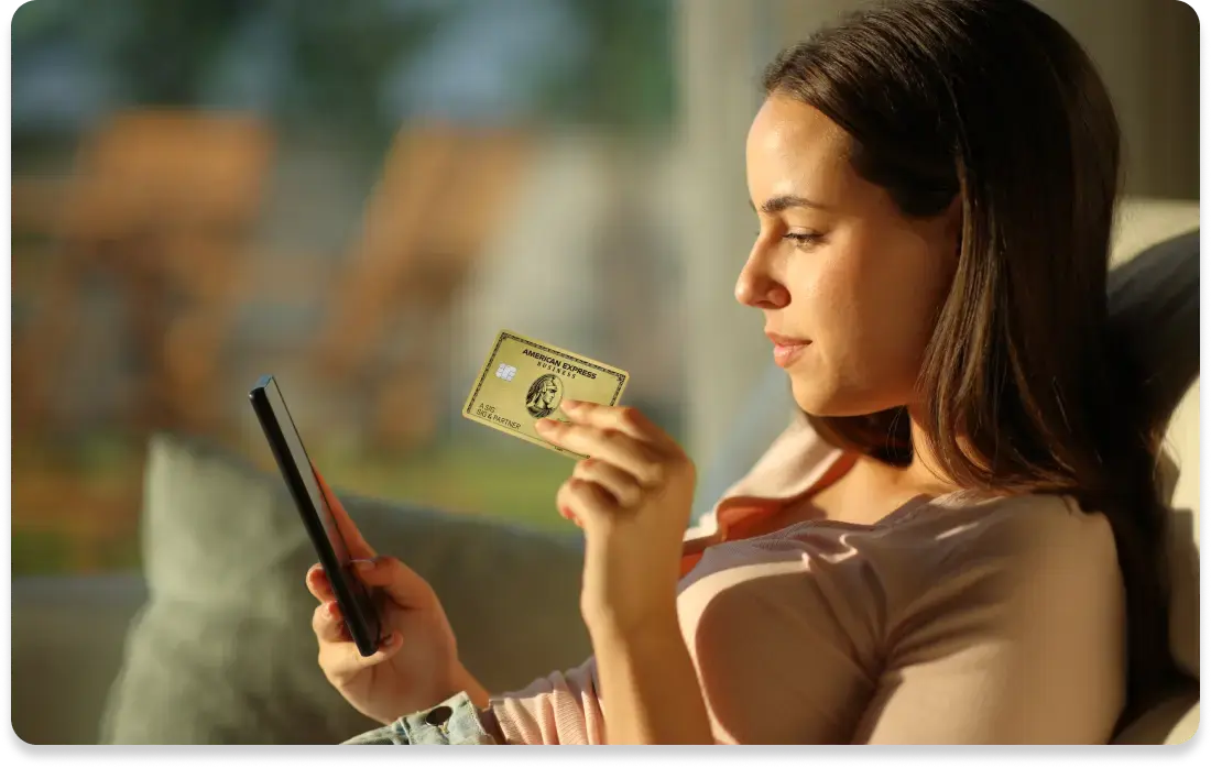 Frau hält eine Business Gold Card in der Hand und schaut auf ihr Smartphone