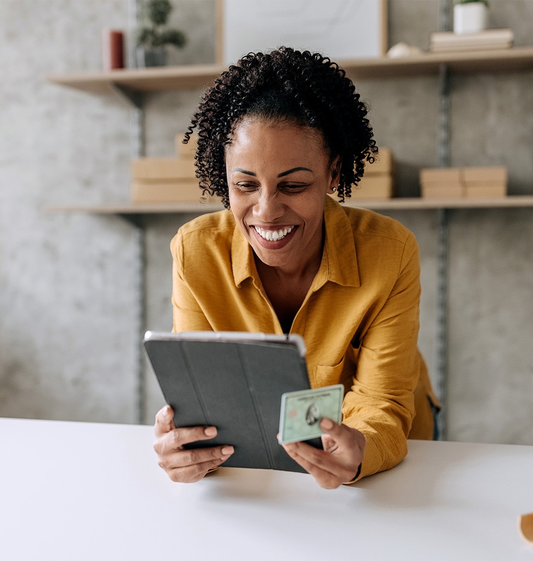 Eine Frau am Tablet mit einer Amex Karte in der Hand