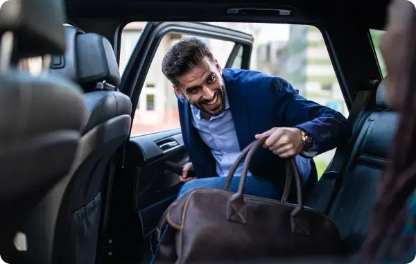 Geschäftsmann steigt mit Reisetasche in ein Auto ein
