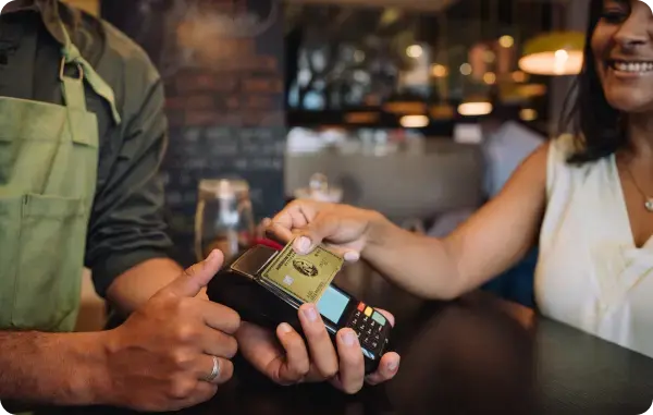 Kundin bezahlt kontaktlos mit einer American Express Business Gold Card an einem Kartenlesegerät