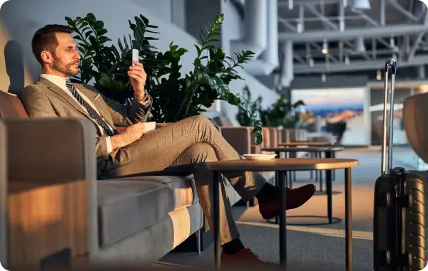 Geschäftsmann sitzt im Flughafen-Lounge-Bereich und nutzt sein Smartphone