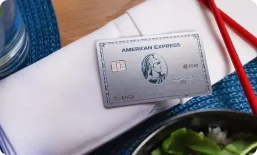 Eine Platinum Plus Card aus Metall liegt auf dem Tisch neben einem Salat und zwei roten Essstäbchen.