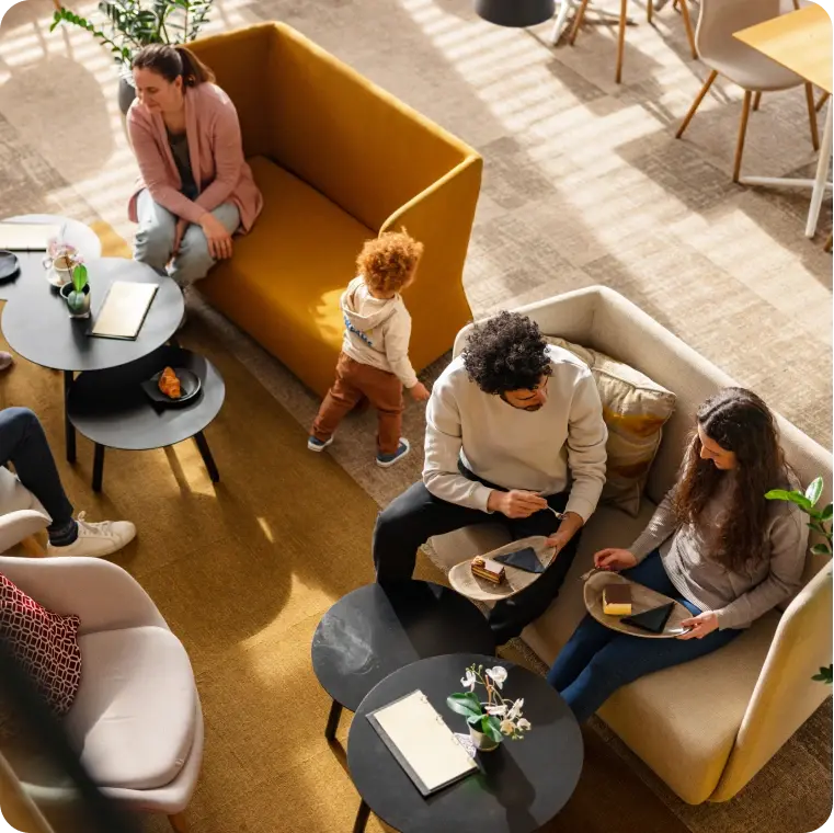 Menschen sitzen in einer Lounge auf Sofas und unterhalten sich bei Kaffee und Gebäck.
