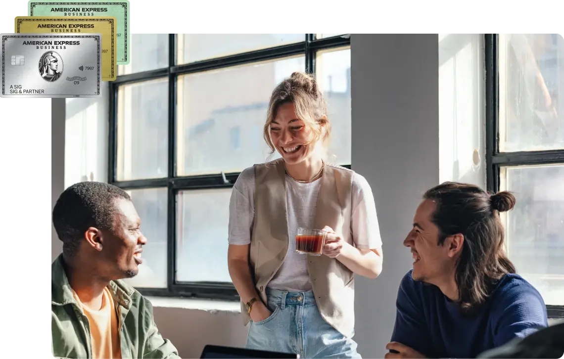 Drei Kolleg:innen lächeln in einem modernen Büro, während miteinander sprechen.