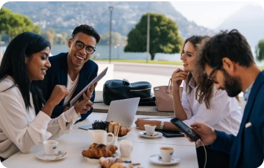 Geschäftspartner:innen sitzen im Freien an einem Tisch und lachen während eines Gesprächs.