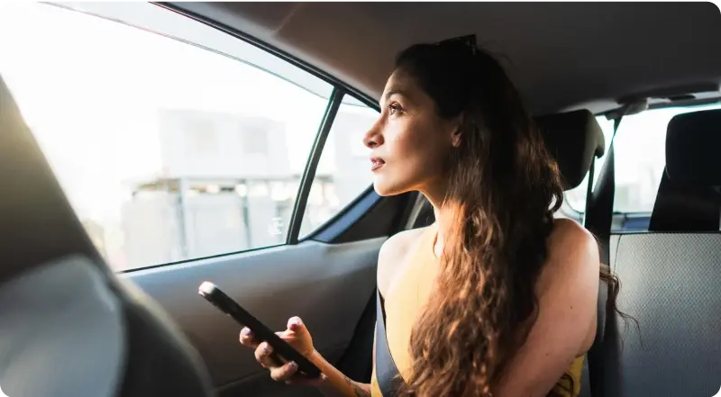 Frau mit Smartphone im Auto – American Express Business Card auch privat flexibel nutzen.