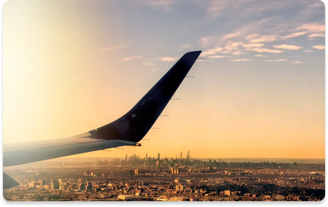 Blick aus einem Flugzeugfenster auf eine Stadt bei Sonnenuntergan