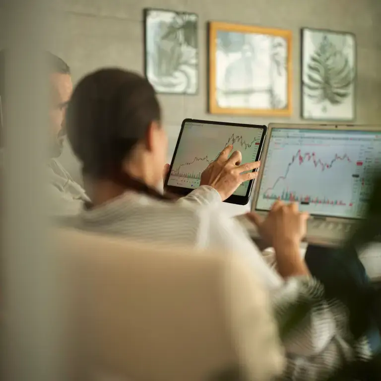 Person analysiert Finanzdaten und Kurscharts auf einem Tablet.
