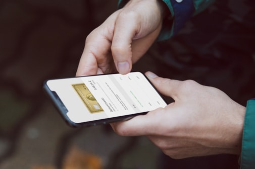 Person hält ein Smartphone in der Hand und verwaltet die Amex App.