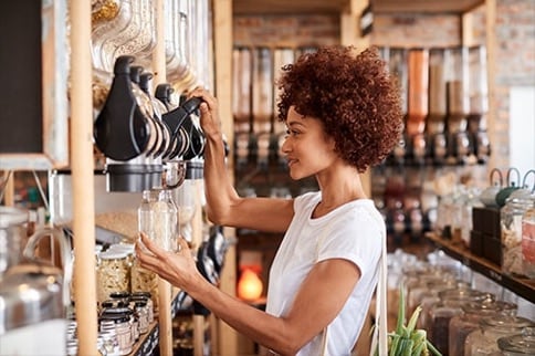 Frau füllt nachhaltigen Behälter in einem Laden auf.