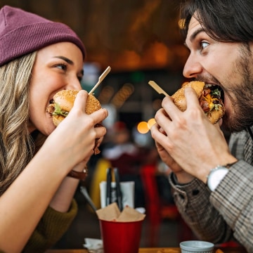 Zwei Personen, die Burger essen