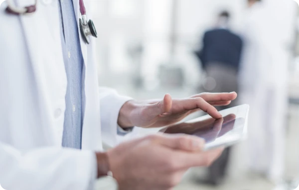 Auslandsreise-Krankenversicherung - Arzt im weißen Kittel hält ein Klemmbrett in der Hand.