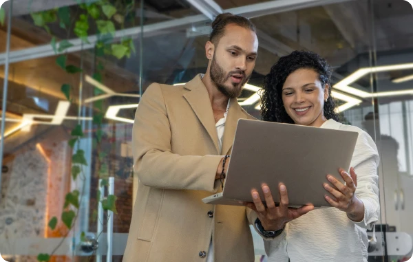 Dell Technologies - Mann und Frau in einem modernen Büro schauen gemeinsam auf ein Laptop und lachen.