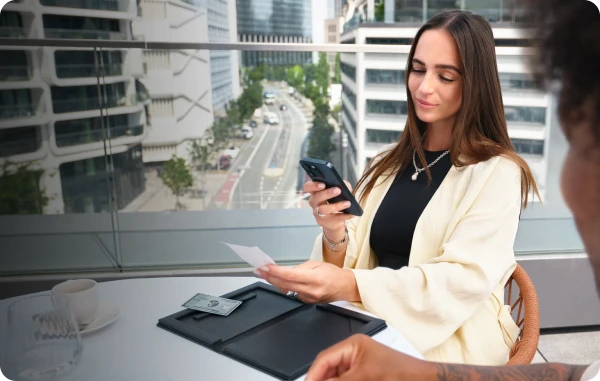 GetMyInvoices - Frau sitzt am Schreibtisch mit Laptop, hält eine Quittung in der Hand und lacht.