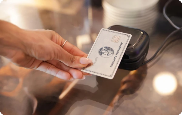 Kontaktloses Bezahlen - Hand reicht eine Karte an ein Lesegerät über einer Kaffeetheke.