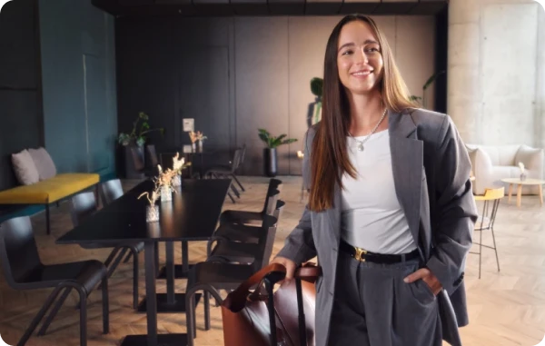 Airport Lounge - Frau mit Handgepäck steht in einer stilvollen Flughafenlounge und lächelt.