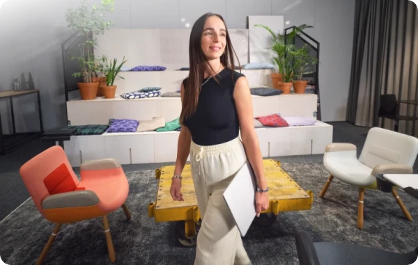 Office Club - Selbstbewusste Frau steht in einem modernen Coworking Space mit bunten Sesseln und stilvoller Einrichtung.