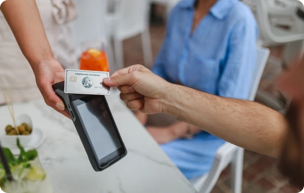 Schutz vor Kartenmissbrauch - Person bezahlt kontaktlos mit Karte an einem Terminal in einem Restaurant