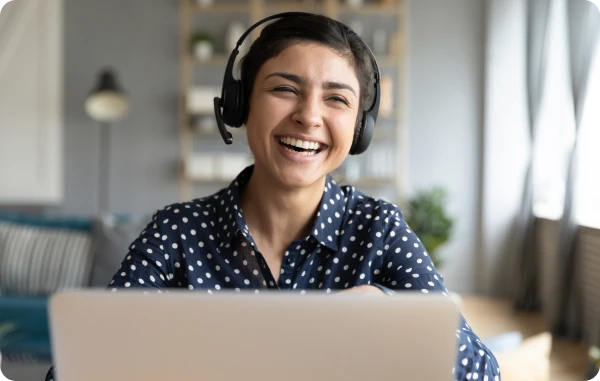 ebuero Telefonservice - Lächelnde Frau mit Headset sitzt an einem Schreibtisch mit Laptop in einem Homeoffice.