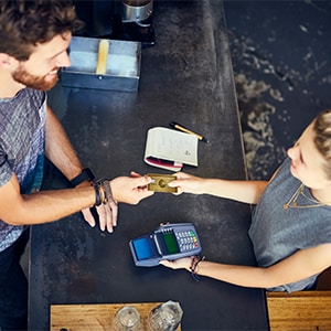 Eine Person bezahlt in einem Geschäft indem Sie ihre American Express Karte in das Kartenterminal steckt und Ihre PIN eingibt